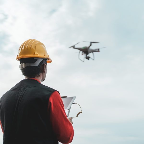male engineer monitoring construction site with drone technology and industrial concept